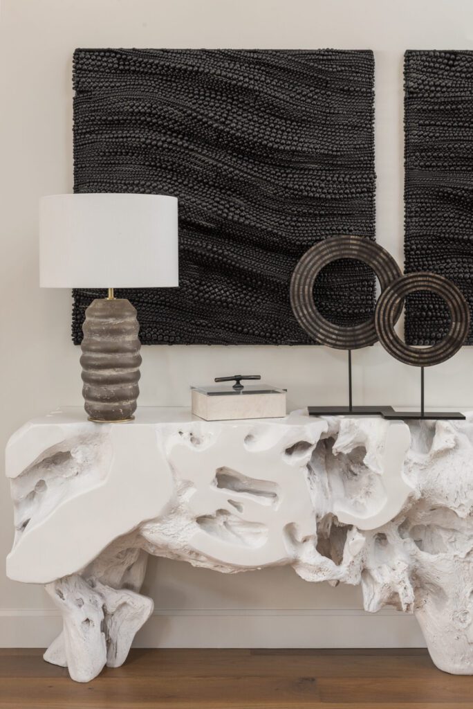 A white table with two lamps and some black art