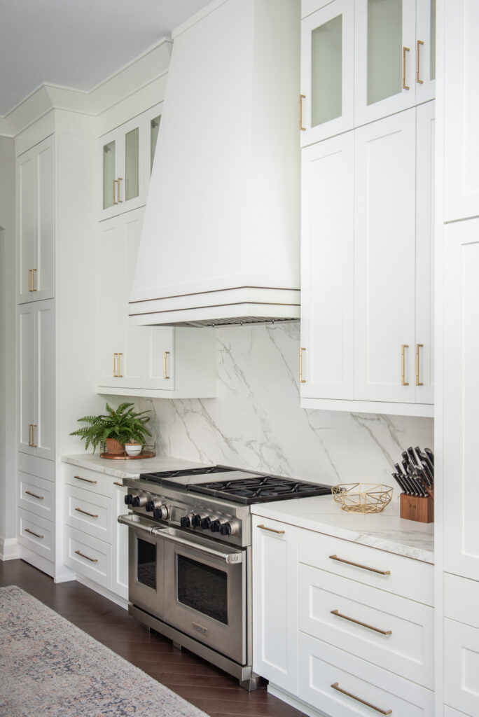 A kitchen with white cabinets and marble countertops.