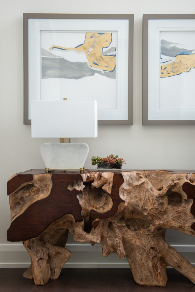 A table with a wooden top and two paintings on the wall.